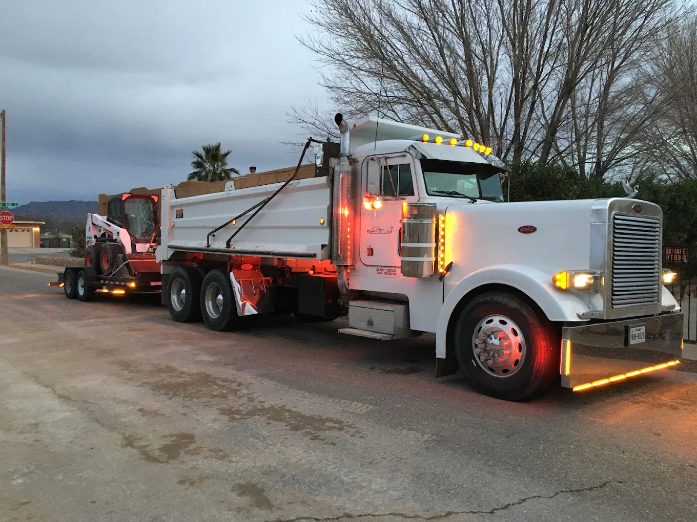 Santa Cruz Trucking dump truck hauling a Bobcat in El Paso